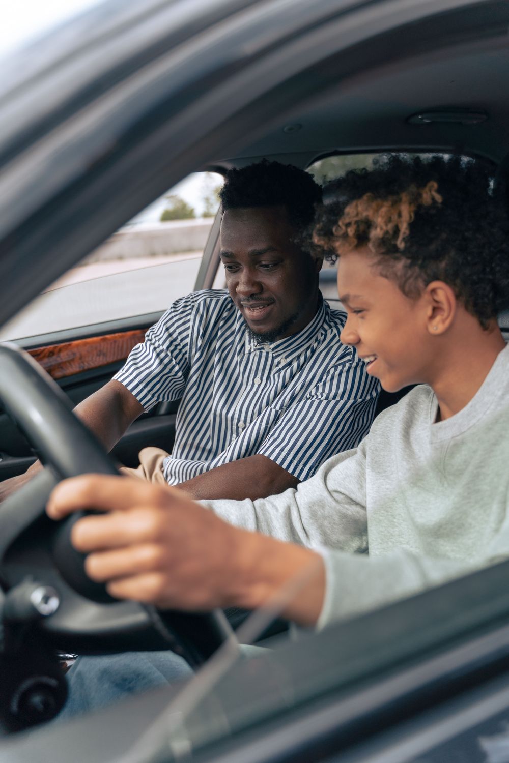 Learner smiling at the wheel beside an instructor